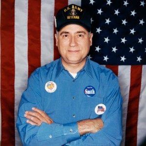 Portrait of a Mature Male Veteran Standing in Front of a Stars and Stripes Flag Wearing Election Badges